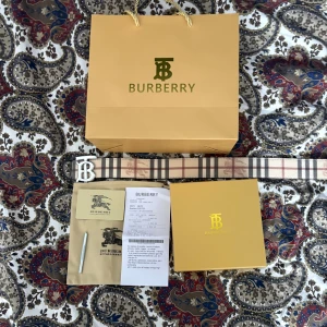 Burberry - Snyggt bälte från Burberry med klassiskt rutigt mönster i beige, brunt och rött. Bältet har ett stort, glänsande guldspänne med Burberrys ikoniska B- logga. Perfekt accessoar för att lyfta din outfit med lyxig känsla.