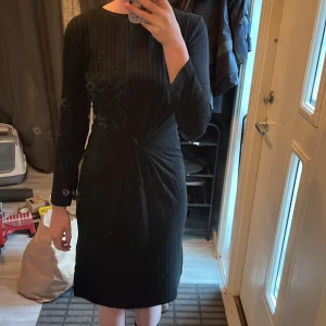 Svart långärmad klänning med twist - Snygg svart klänning kort ärm och rund hals. Den är lite kort men jag skulle tippa på att en person som är 160cm lång hade passat perfekt i den.😊Jag är 166cm lång. Den har en twistad detalj i midjan som ger en cool form och en slits på sidan för extra edge. Materialet är mjukt och har en lätt ribbad struktur som gör den unik. Perfekt för dig som gillar stilrena och moderna plagg.