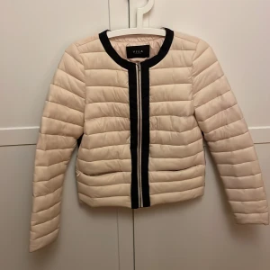 Söt höstjacka  - Snygg rosa pufferjacka från VILA i storlek XS. Jackan har svarta detaljer vid krage och dragkedja, samt horisontella quiltade partier. Långärmad och med praktiska fickor på sidorna. Perfekt nu till hösten
