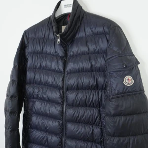 Moncler jacka  - Säljer nu en riktigt stilren jacka från Moncler. Modellen heter Lambot Giubbotto. Storlek 2 som motsvarar m, färgen är navy! Skriv för frågor. Självklart äkta. 