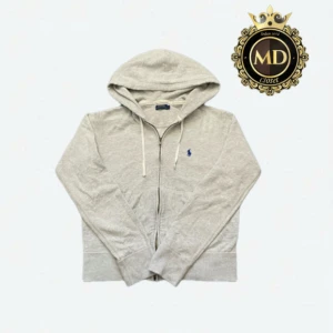 Polo Ralph Lauren hoodie  - Ljusgrå hoodie från Polo Ralph Lauren med dragkedja, huva och snörning. Klassisk blå logga broderad på bröstet. Tillverkad i mjuk bomullsmix och har långa ärmar samt ribbade muddar. Perfekt för chill dagar eller när du vill ha en clean look. Tröjan är i mycket bra skick. Storleken på tröjan är L men passar som M! Skriv vid frågor eller mer bilder⚜️