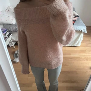 Ljusrosa stickad offshoulder tröja -  Ljusrosa stickad tröja med offshoulder-design och bred ribbad kant upptill. Tröjan har långärmade ärmar och är fluffig och mjuk i materialet. Passformen är lite större och oversized för att vara i storlek XS, så skulle även säga att den passar S och M. Den har defekter som små fläckar och är lite nopprig. Köpt på Vinted för 140 kr. 