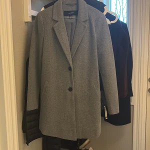 Grå kappa från Vero Moda - Snygg grå kappa från Vero Moda med klassisk krage och två svarta knappar framtill. Nästintill aldrig använd