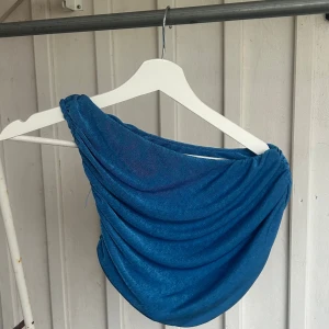 Blå one-shoulder topp - En glittrig, blå one-shoulder topp. Perfekt festtopp!