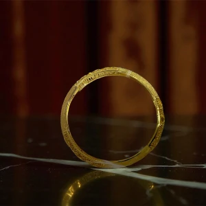 Guldfärgat armband med gravyr - Snyggt guldfärgat armband med detaljerad gravyr och elegant rund form. Armbandet har en klassisk och tidlös look som passar perfekt för dig som gillar stilrena accessoarer med en touch av lyx.