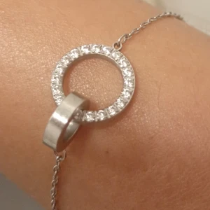 Silverarmband med cirkel och stenar - Snyggt armband i silver från Edblad med tunn kedja och dekorativ cirkel som är prydd med glittrande stenar. En slät ring hänger i cirkeln för en cool och modern look. Perfekt för dig som gillar stilrena detaljer.