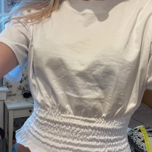 Vit croppad topp med smockad midja - Vit figurformad och rynkad tshirt från Stradivarius, köpt på Zalando