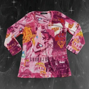 Färgstark långärmad tröja Passport - Unik långärmad tröja från Passport med coolt tryck i rosa, lila, orange och inslag av blått. Tröjan har ett grafiskt mönster med text och motiv inspirerade av Guanajuato, Mexico. Rund hals och mjukt, stretchigt material som känns skönt mot huden.