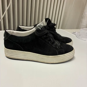 Svarta sneakers från Philip Hog  - Svarta, stilrena sneakers från Philip Hog med platt, vit sula och snörning. Ovandelen är i mocka med detaljer i blankt skinn vid hälen och vit insida. Snyggt logomärke bak och på plösen. 