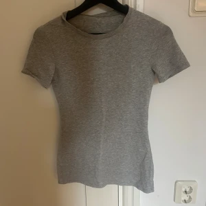 Grå t-shirt från Intimissimi, S - En enkel och stilren grå t-shirt från Intimissimi i mjuk bomull. Modellen är figurnära med rund hals och korta ärmar, perfekt för en clean och chill look. Supima Cotton-materialet gör den extra skön mot huden.