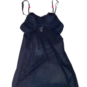 Svart nattklänning   - Svart transparent kortklänning med tunna axelband och små röda rosdetaljer på banden. Plagget är i gott skick och har bara använt den en gång eftersom kupan inte passar mig. 