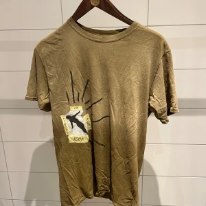 Cactus Jack khaki t-shirt Travis Scott - Säljer en brun t-shirt från Cactus Jack x Travis Scott i storlek M. T-shirten har tryck med texten 'Highest in the Room' och siluett på framsidan samt grafiskt Cactus Jack-tryck på ryggen. Klassisk rund hals och korta ärmar. Materialet är mjuk bomull.