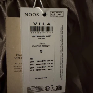 Brun långkjol från Vila - Snygg siden långkjol från Vila i en mjuk brun nyans. Kjolen har ett brett midjeband och ett glansigt, flowy tyg som ger en lyxig känsla. Perfekt för dig som gillar stilrena och trendiga plagg.