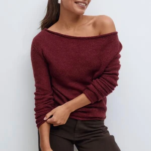 Vinröd offshoulder stickad tröja - Snygg vinröd stickad tröja med offshoulder-design och lång ärm. Tröjan har en mjuk och skön känsla, perfekt för dig som gillar en lite chill och trendig look. Den är använd typ 2 gånger.