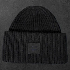 Svart ribbstickad mössa från Acne Studios - Svart ribbstickad mössa från Acne Studios med bred uppvikt kant och det ikoniska Face-logotypen framtill. Klassisk och stilren design som passar perfekt till kalla dagar. Tillverkad i mjukt och värmande material.