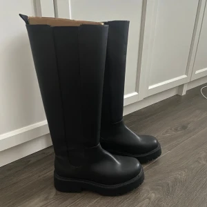 Svarta höga boots med platt sula - Stilrena svarta boots med högt skaft och chunky platt sula. 
