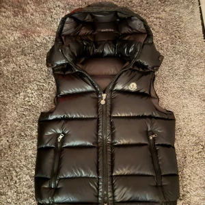 Moncler väst svart - hej! säljer nu min gamla moncler väst i helt okej skick, storlek 3 men liten i storleken så passar även M perfekt! västen är ju en gammal model så inte nfc scan men om ni är nog kunniga så ser ni att västen är äkta, inget kvitto tyvär. ända stället den är lite trasig är på ”cartoonen” inget mer! kom gärna med bud och frågor om ni har några:) 
