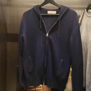 Mörkblå kashmirhoodie från Sayless - Mysig mörkblå hoodie från Sayless i lyxig kashmir. Tröjan har dragkedja framtill, huva med snören och två fickor. Perfekt för dig som gillar en stilren och bekväm look med premiumkänsla. Sitter mer som xs!