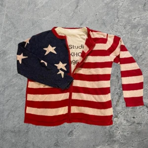 Cardigan från Heirloom Collectibles - Unik kofta med dragkedja från Heirloom Collectibles. Ena sidan har marinblått med vita stjärnor, andra sidan är röd och beige-randig. Baksidan är röd med randig och stjärnmönstrad ärm. Materialet är 55% ramie och 45% bomull. Perfekt för dig som gillar statement-plagg. Passar bra nu när de börjar bli lite kallare. Om du undrar något är det bara att höra av sig✅