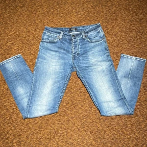 Blå skinny jeans från Neuw - Snygga blå jeans från Neuw med skinny passform och klassisk femficksdesign. Jeansen har en ljus tvätt med slitningar och kontrastsömmar, samt knapp och dragkedja i midjan. Perfekta för dig som gillar en smal siluett och modern look.