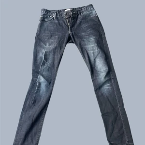 Mörkblå jeans från Acne - Säljer ett par mörkblå slim fit jeans från Acne Jeans med snygga slitningar och klassisk femficksdesign. Jeansen har en smal passform, normal midja och är tillverkade i stretchig denim för extra komfort. Perfekta för dig som gillar en stilren och modern look.