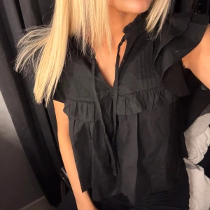 Svart blus med volang - Säljer en söt svart blus med volangdetaljer från GinaTricot. Fint skick 🤍
