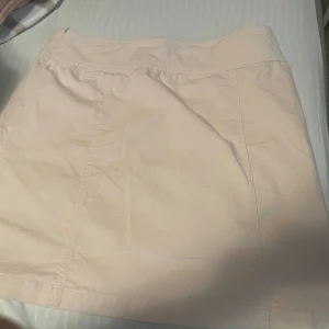 Ljusrosa kortkjol från Åhléns - Supersöt ljusrosa kortkjol från Åhléns i mjuk bomull med lite stretch. Smalrandig manchester typ. Kjolen har enkel design utan mönster och är perfekt för dig som gillar en clean och stilren look. Materialet är 97% bomull och 3% elastan för extra komfort.