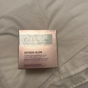 Filorga Oxygen-Glow Radiance Cream - Filorga Oxygen-Glow är en super-perfekterande ansiktskräm som jämnar ut, återfuktar och ger glow. Kommer i en lyxig roséguldig förpackning. Innehåller hyaluronsyra och L-enzym för extra boost och detox.