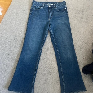 Blå bootcut jeans från &Denim - Snygga blå bootcut jeans från &Denim i klassisk denim med hög midja. Jeansen har fem fickor, dragkedja och knapp framtill samt en lätt utsvängd passform nertill. Väldigt skönt material.