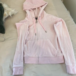 Ljusrosa Juicy Couture hoodie XS - Supermjuk ljusrosa hoodie från Juicy Couture i velour med dragkedja, huva och snörning. Klassisk logga broderad på bröstet och två fickor framtill. Perfekt för en chill och trendig look.