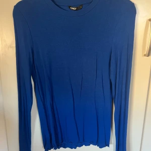 Blå långärmad tröja från ONLY - Säljer en enkel och stilren blå långärmad tröja från ONLY i storlek S. Tröjan har rund halsringning och är figurnära i modellen. Den är väldigt stretchig och oerhört mjuk. Perfekt att matcha med jeans eller kjol för en clean look.