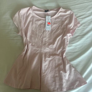 Peplum top, Ballet slipper från Gina Tricot  - Den rosa toppen har aldrig blivit använd då etiketten sitter kvar. Toppen har en ljuvlig ljus nyans färg av rosa. Den är stretchig och inte alls så genomskinlig som man tror 