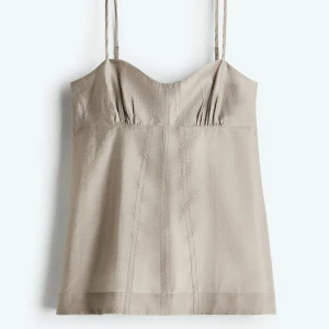 Beige linnetopp med tunna axelband - Snygg beige/grå topp med tunna axelband och lätt rynkade detaljer vid bysten. Toppen har en rak passform och är tillverkad i ett mjukt, svalt material. Helt ny med lapp kvar!! 