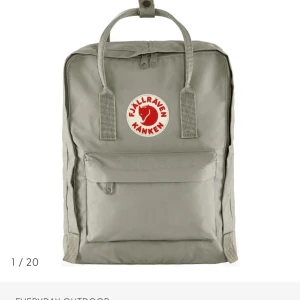 Grå Kånken ryggsäck från Fjällräven - Säljer en klassisk grå Kånken ryggsäck från Fjällräven med ikonisk röd och vit logotyp framtill. Väskan har ett fyrkantigt format, slitstarka handtag och justerbara axelremmar. Praktisk framficka med dragkedja och tillverkad i tålig syntet.