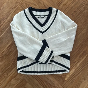 Vit stickad v-ringad tröja Gina Tricot - Snygg vit stickad tröja från Gina Tricot med mörkblå ränder. Tröjan är helt ny och aldrig använd.😊