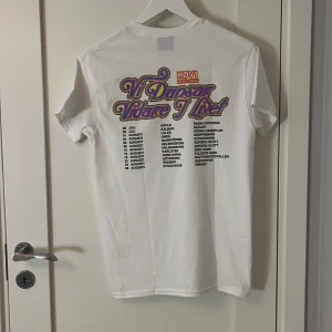 Vit HOV1 t-shirt med tourtryck, S - Helt ny oanvänd vit t-shirt från HOV1 i storlek S, med ett litet kronemblem på bröstet och stort färgglatt tourtryck på ryggen med texten 'Vi Dansar Vidare I Livet' och turnédatum. Klassisk rund hals och korta ärmar.  Högt pris då den är helt slutsåld och är Limited edition.