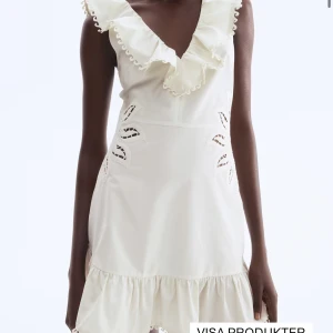 Vit kortklänning med volang och broderi hm  - Supersöt vit kortklänning med djup v-ringning och volangkant. Klänningen har broderade detaljer i midjan och en volang längst ner. Perfekt för sommarens alla tillfällen, med en romantisk och fräsch vibe.