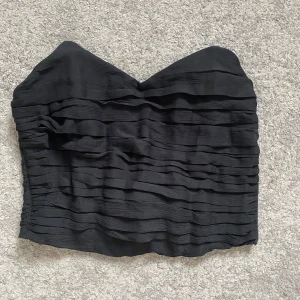 Svart bandeau tubtopp från BikBok - Säljer en svart bandeau tubtopp från BikBok med snygga vågiga volanglager och hjärtformad urringning. Aldrig använd 🪩