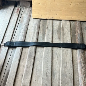 Svart sadelgjord från Fairlfield - Säljer en svart sadelgjord från Fairfield i storlek 140, perfekt för dig som rider. Gjorden är tillverkad i slitstark syntet med mönstrad yta och har dubbla metallspännen i båda ändar. Snyggt randigt band längs mitten och robust konstruktion för extra komfort till hästen.