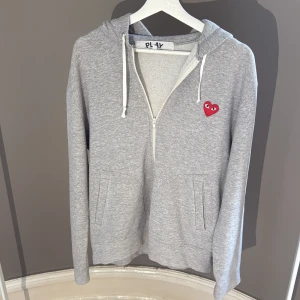 Grå cdg zip hoodie  - Grå hoodie från Cdg i storlek L. Tröjan har dragkedja, huva med snörning och flera röda hjärtan på ryggen mycket bra skick storlek L