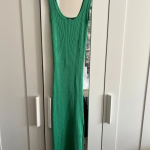 Grön ribbad långklänning - Säljer en snygg grön ribbad långklänning från gina. Klänningen är ärmlös med rund halsringning och har en tight passform som framhäver figuren. 