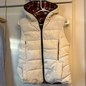 Vit dunväst med huva från Zara - Snygg vit TRF puffer-väst med huva & röd-svartrutig insida  Perfekt för Y2K / retro streetwear. Mena även andra stilar så som casual. Köpt runt 2005/2007.  ✔️ Mysig & varm ✔️ Passar över hoodie eller crewneck ✔️ Rare TRF piece – svår att hitta idag
