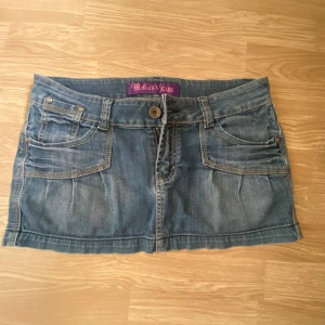 INTRESSEKOLL - Snygg blå jeanskjol från Monica's Jeans i storlek L. Kjolen har klassiska fickor fram och bak, samt coola dragkedjor på bakfickorna. Tillverkad i 98% bomull och 2% spandex för en bekväm passform. Perfekt för dig som gillar streetstyle och denim. Upplever den som liten i storleken. 