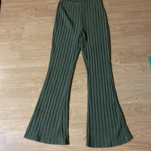 Gröna ribbade wide byxor - Snygga gröna byxor med breda ben och ribbad struktur. De har hög midja och är tillverkade i ett mjukt, stretchigt material som ger en skön passform. Perfekta för dig som gillar en trendig och avslappnad stil.