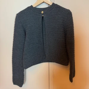 Mörkgrå kofta från Zara i stickat - Jättefin mörkgrå kofta från Zara i stickat material med strukturerat rutmönster. Koftan har rund halsringning, lång ärm och stängs med en guldfärgad knapp upptill. Jag säljer denna tröjan för 200kr + frakt som kunden betalar, pris kan diskuteras 