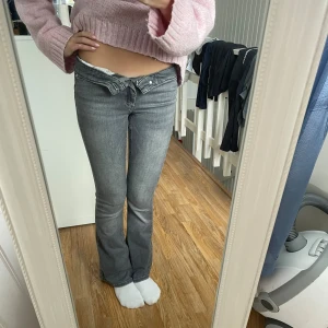 Grå bootcut jeans med medel midja - Snygga grå jeans med bootcut och medel midja. Materialet är stretchigt jeans som sitter tajt över låren och släpper ut vid benslutet. Perfekta för en trendig och avslappnad look.