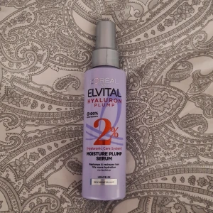 L'Oréal Elvital Hyaluron Plump Serum - Lila plastflaska med silvrig pump, 150 ml. Elvital Hyaluron Plump Moisture Plump Serum med 2% hyaluronsyra för återfuktning och volym. Perfekt för torrt hår, leave-in formula som inte tynger ner. Snygg design och enkel att använda.