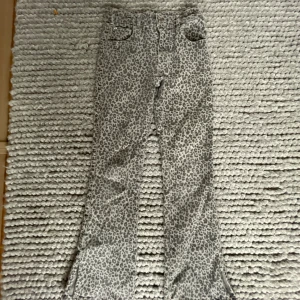Leopardmönstrade low waist bootcut byxor från Zara - Snygga bootcut byxor från Zara i storlek 152 11-12 år storlek. Med grått leopardmönster. Byxorna har klassisk femficksdesign, bälteshällor och är tillverkade i ett mjukt bomullstyg. Perfekta för dig som vill sticka ut med ett coolt mönster men men kan perfekt klä ner byxorna med en vit stickad tjocktröja till exempel