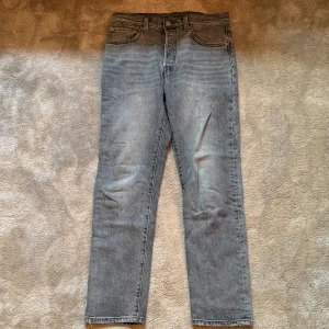 Grå Levis 501 jeans straight fit - Säljer ett par klassiska Levis 501 jeans i grå tvätt. De har rak passform, fem fickor och knappgylf. Jeansen är tillverkade i bomull och har den ikoniska Levis-lappen bak i midjan. Perfekta för en avslappnad och tidlös stil. Vid eventuella frågor hör av er!