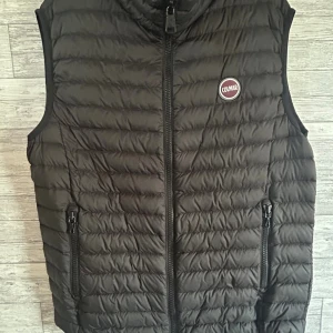 Svart dunväst från Colmar - Svart dunväst från Colmar med quiltad design och dragkedja framtill.  Storlek - M. För referens : 184cm och passar bra. 